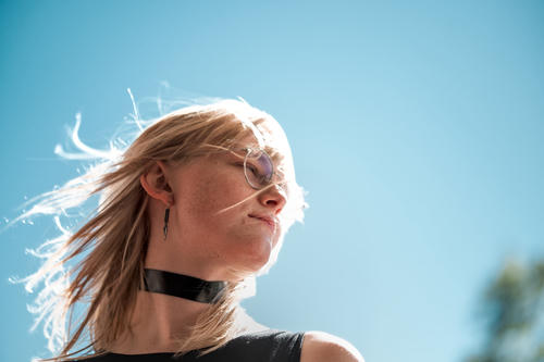 Photograph of a young woman looking up and off into the distance, sun
  glinting off her hair.