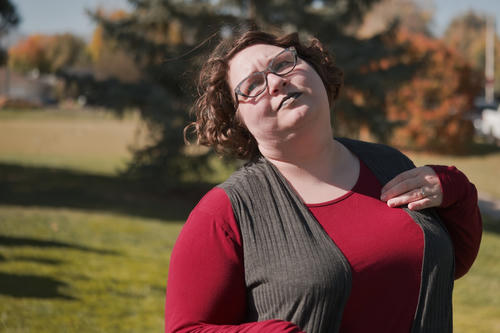 Photograph of a young woman bent backwards as though she has just heart something, looking skeptical.