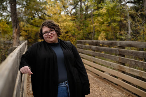 Photograph of a young woman on a bridge, smiling warmly.