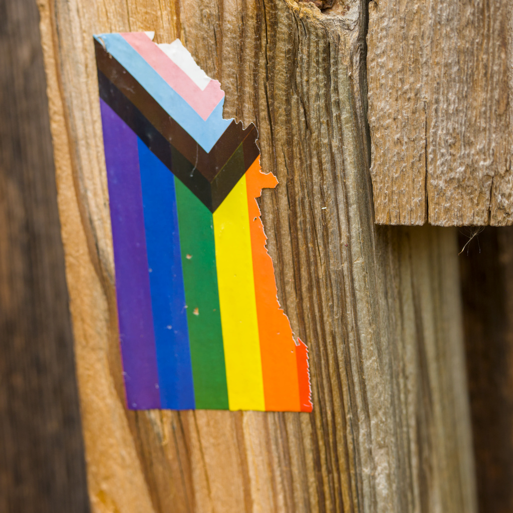 A progress pride sticker that's been pulled away at the red edge